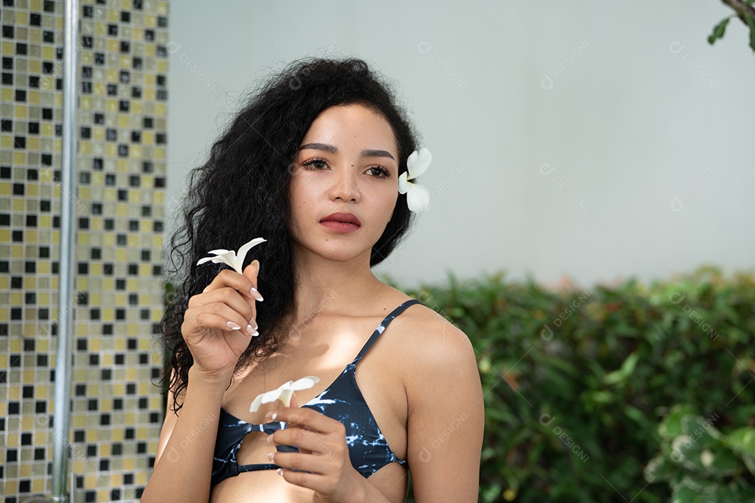 Corpo bronzeado magro de jovem em biquíni em folhas de palmeira.