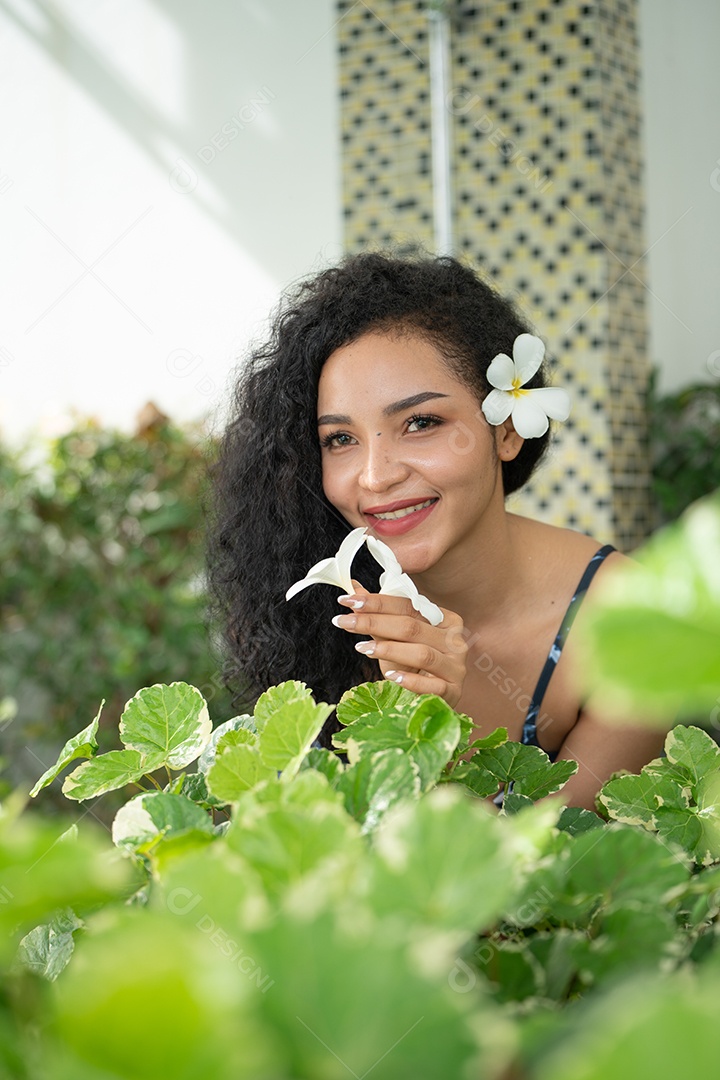 Corpo bronzeado magro de jovem em biquíni em folhas de palmeira.
