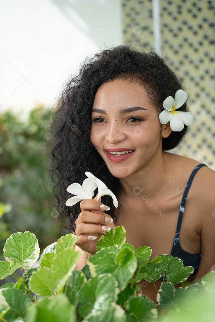 Corpo bronzeado magro de jovem em biquíni em folhas de palmeira.