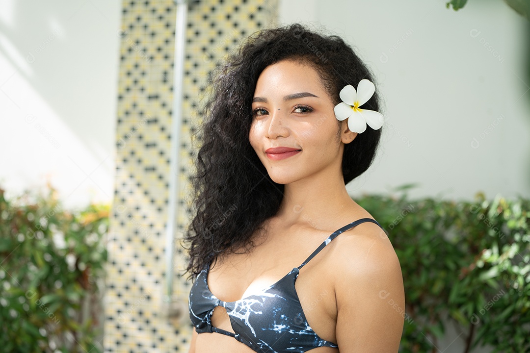 Corpo bronzeado magro de jovem em biquíni em folhas de palmeira.