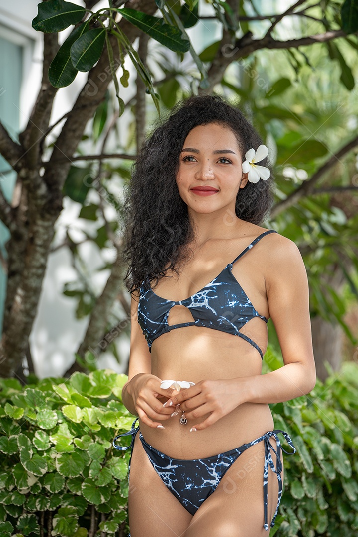 Corpo bronzeado magro de jovem em biquíni em folhas de palmeira.