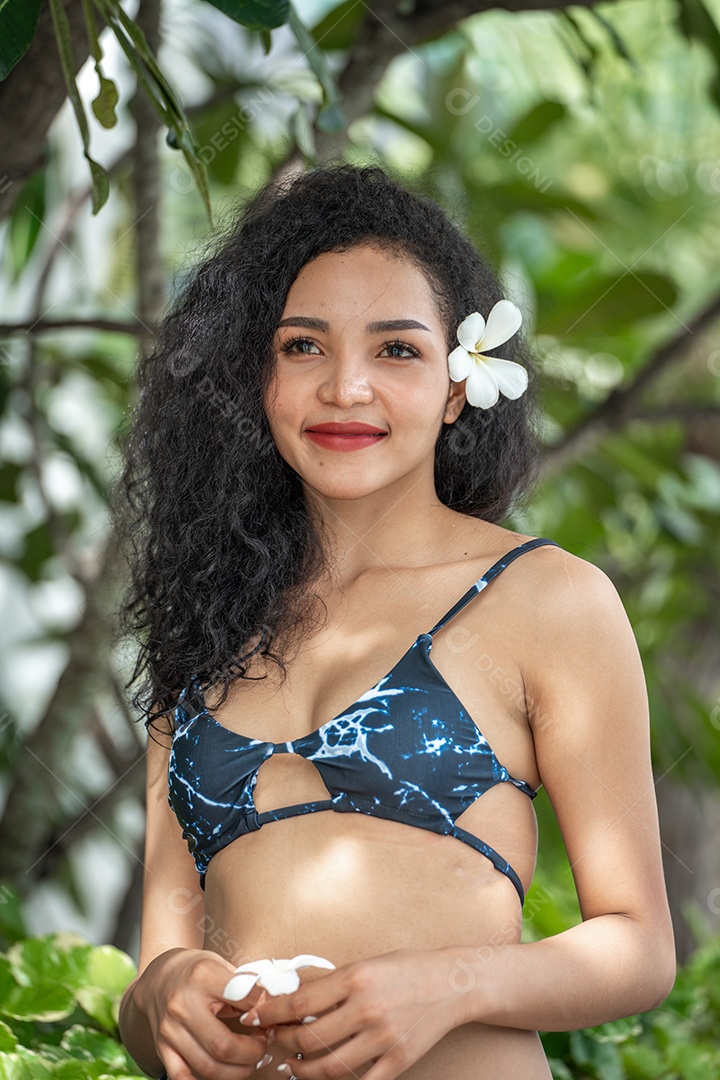 Corpo bronzeado magro de jovem em biquíni em folhas de palmeira.