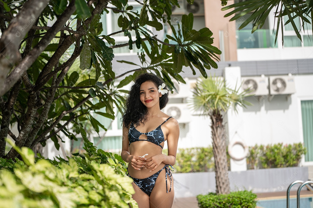 Corpo bronzeado magro de jovem em biquíni em folhas de palmeira.