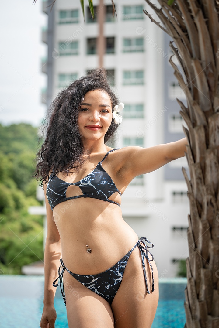 Corpo bronzeado magro de jovem em biquíni em folhas de palmeira.