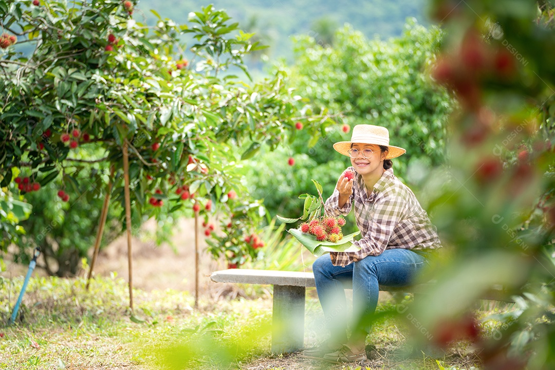 Agricultora asiática, agricultora segurando pilha de frutas.