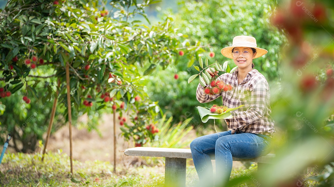 Agricultora asiática agricultora segurando pilha frutas.