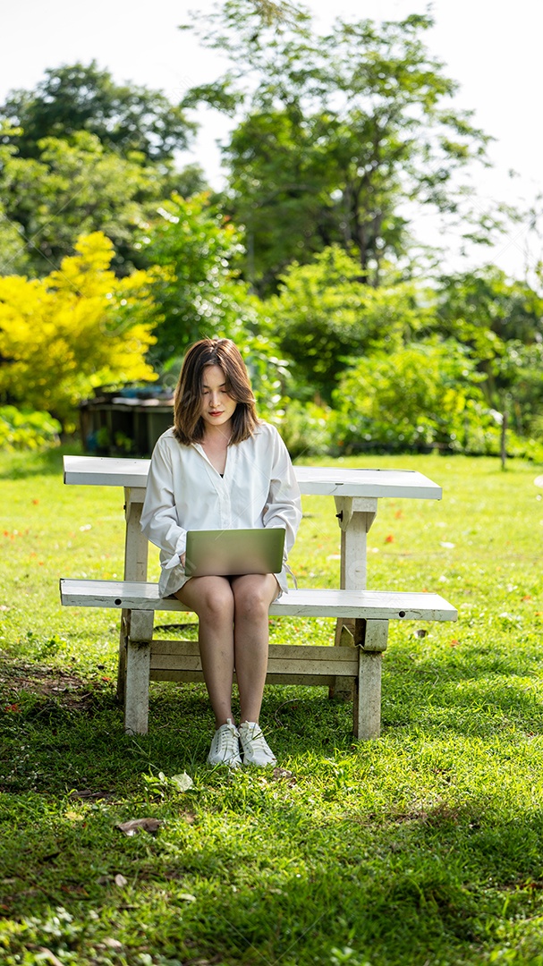 Mulher de sorriso pensativo no parque usando tablet digital inteligente.