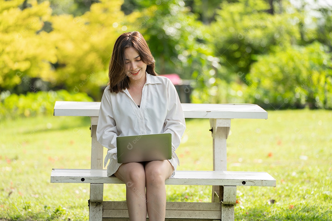 Mulher de sorriso pensativo no parque usando tablet digital inteligente.