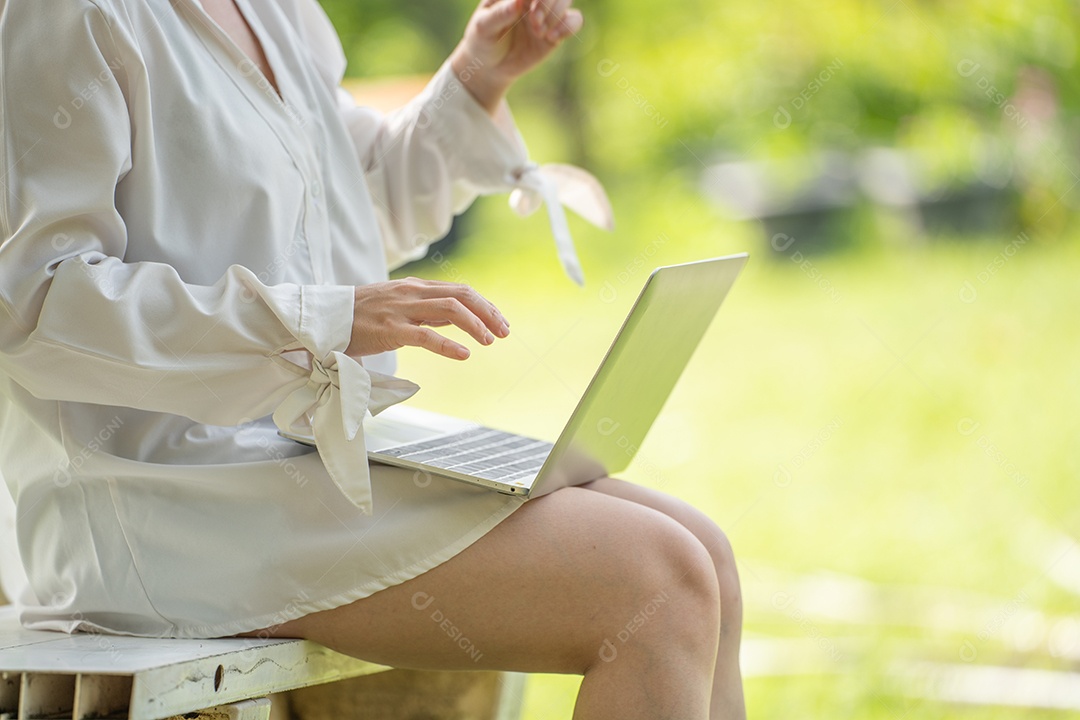 Mulher de sorriso pensativo no parque usando tablet digital inteligente.