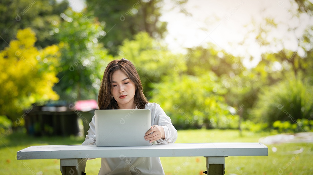 Mulher de sorriso pensativo no parque usando telefone inteligente.