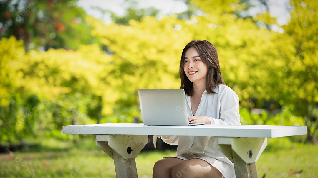 Mulher de sorriso pensativo no parque usando telefone inteligente.