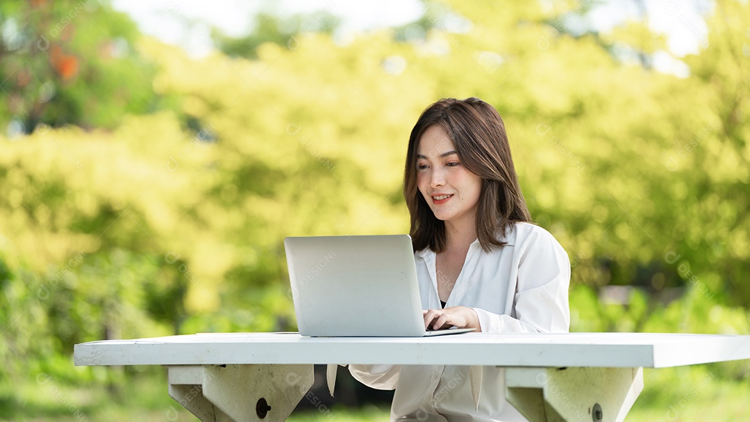 Mulher de sorriso pensativo no parque usando telefone inteligente.