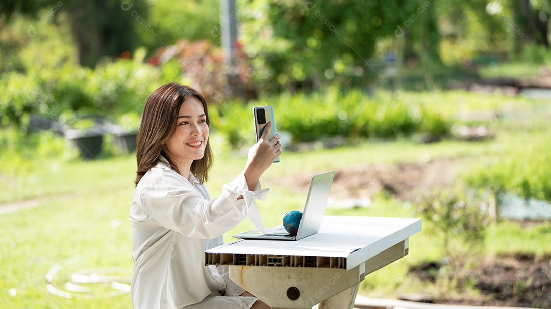 Mulher de sorriso pensativo no parque usando telefone inteligente.