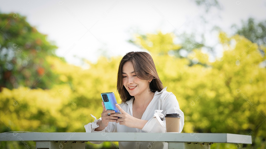 Mulher de sorriso pensativo no parque usando telefone inteligente.