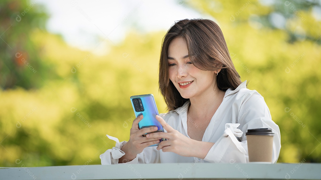 Mulher de sorriso pensativo no parque usando telefone inteligente.