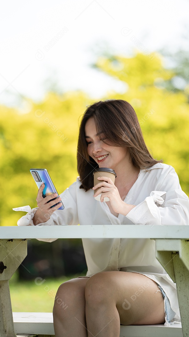 Mulher de sorriso pensativo no parque usando telefone inteligente.