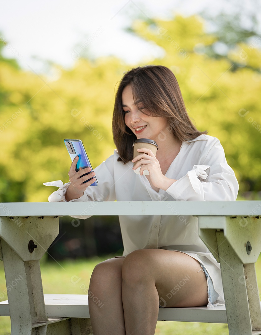 Mulher de sorriso pensativo no parque usando telefone inteligente.
