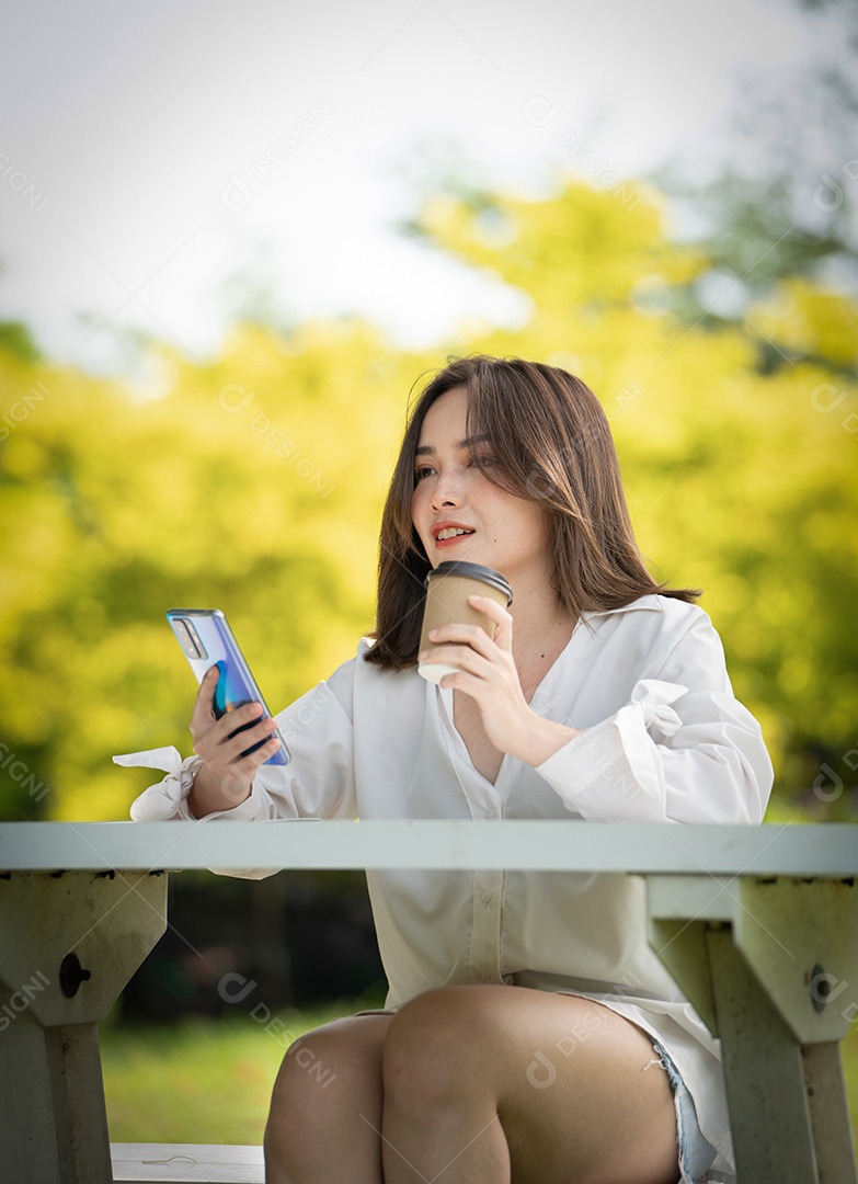 Mulher de sorriso pensativo no parque usando telefone inteligente.