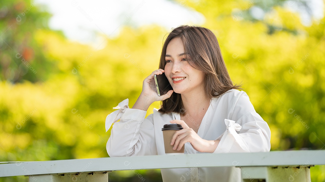 Mulher de sorriso pensativo no parque usando telefone inteligente.