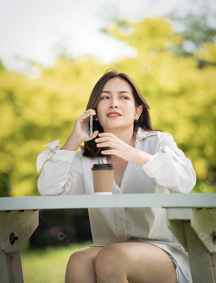 Mulher de sorriso pensativo no parque usando telefone inteligente.