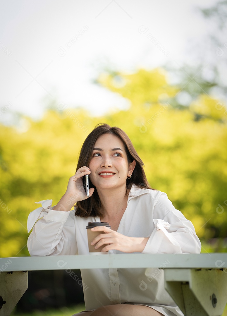 Mulher de sorriso pensativo no parque usando telefone inteligente.