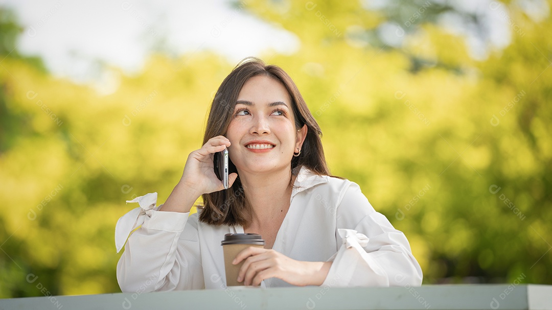 Mulher de sorriso pensativo no parque usando telefone inteligente.