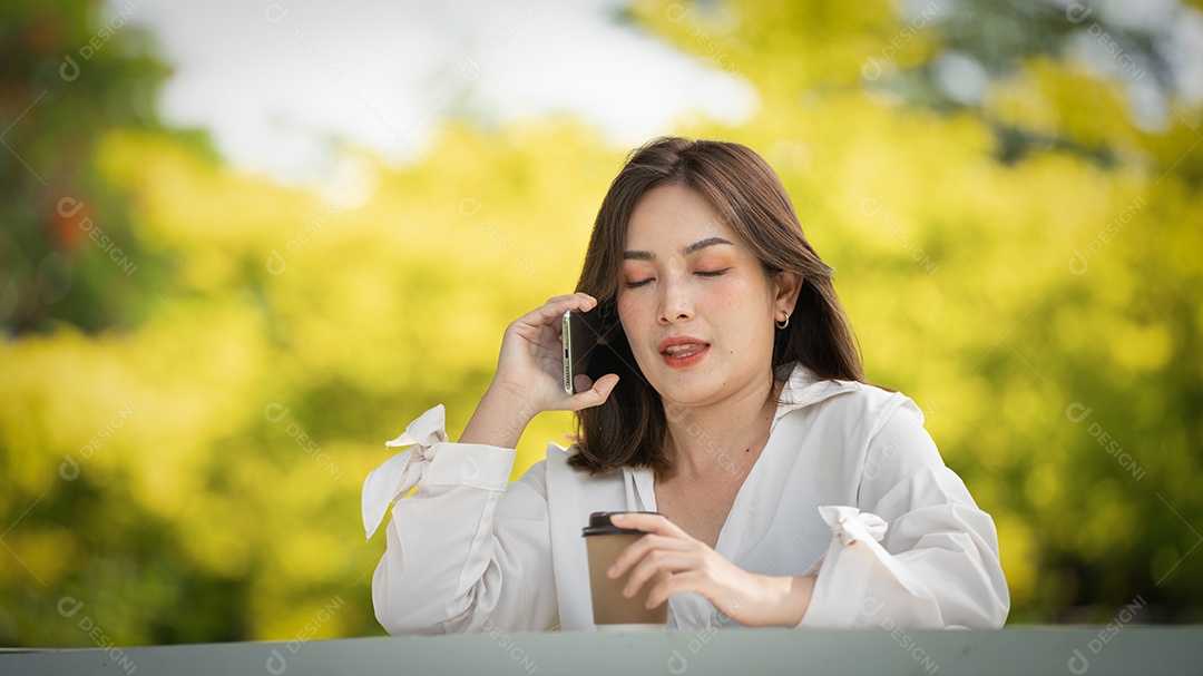 Mulher de sorriso pensativo no parque usando telefone inteligente.