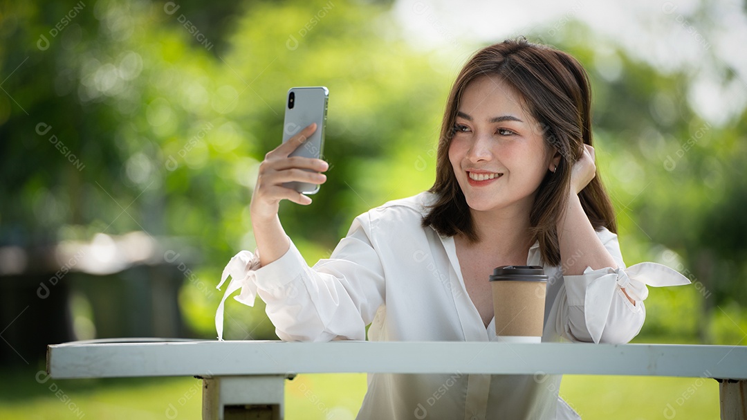 Mulher de sorriso pensativo no parque usando telefone inteligente.