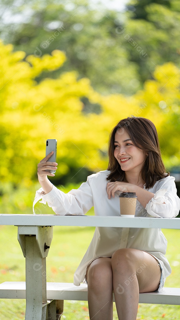 Mulher de sorriso pensativo no parque usando telefone inteligente.