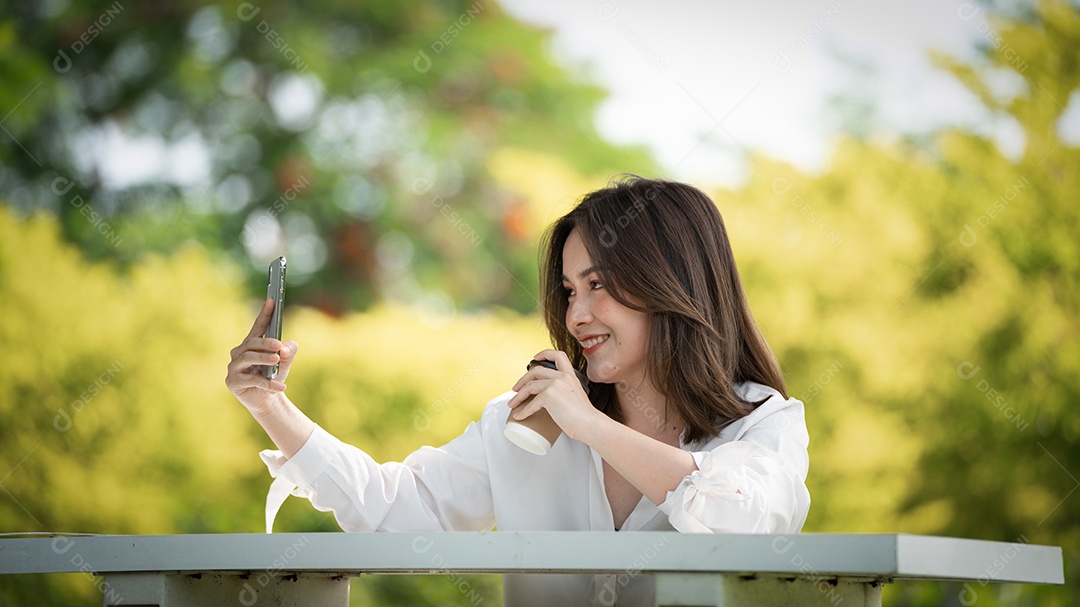 Mulher de sorriso pensativo no parque usando telefone inteligente.
