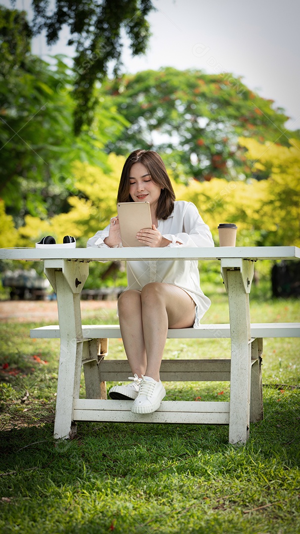 Menina linda jovem de camisa bege posando na cidade verde.