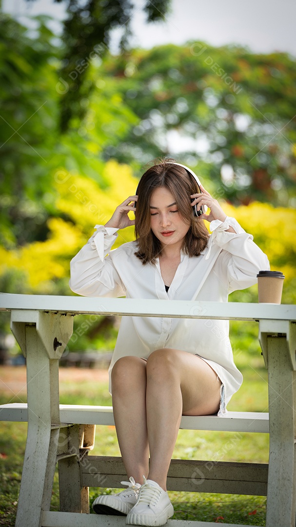 Menina linda jovem de camisa bege posando na cidade verde.