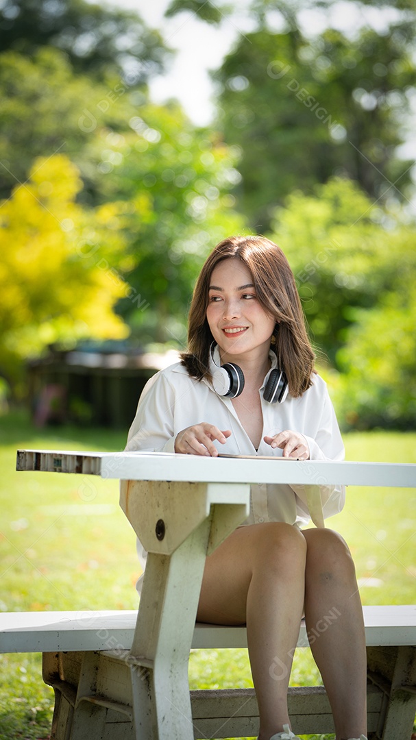Menina linda jovem de camisa bege posando na cidade verde.