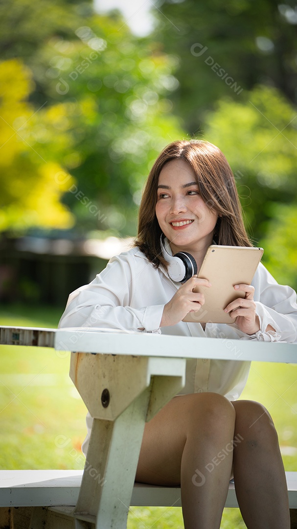 Menina linda jovem de camisa bege posando na cidade verde.