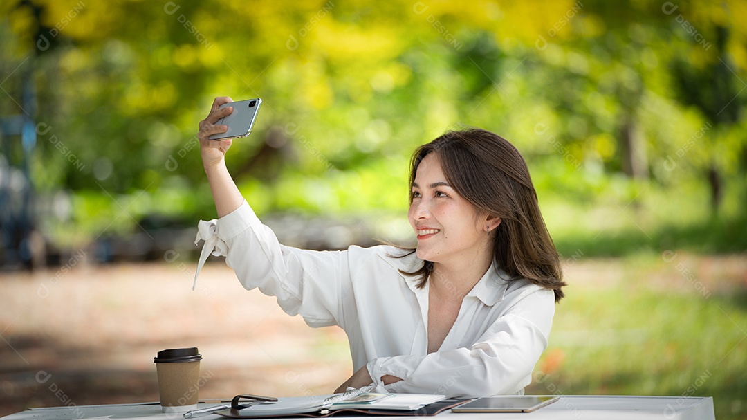 Mulher de sorriso pensativo no parque usando telefone inteligente.