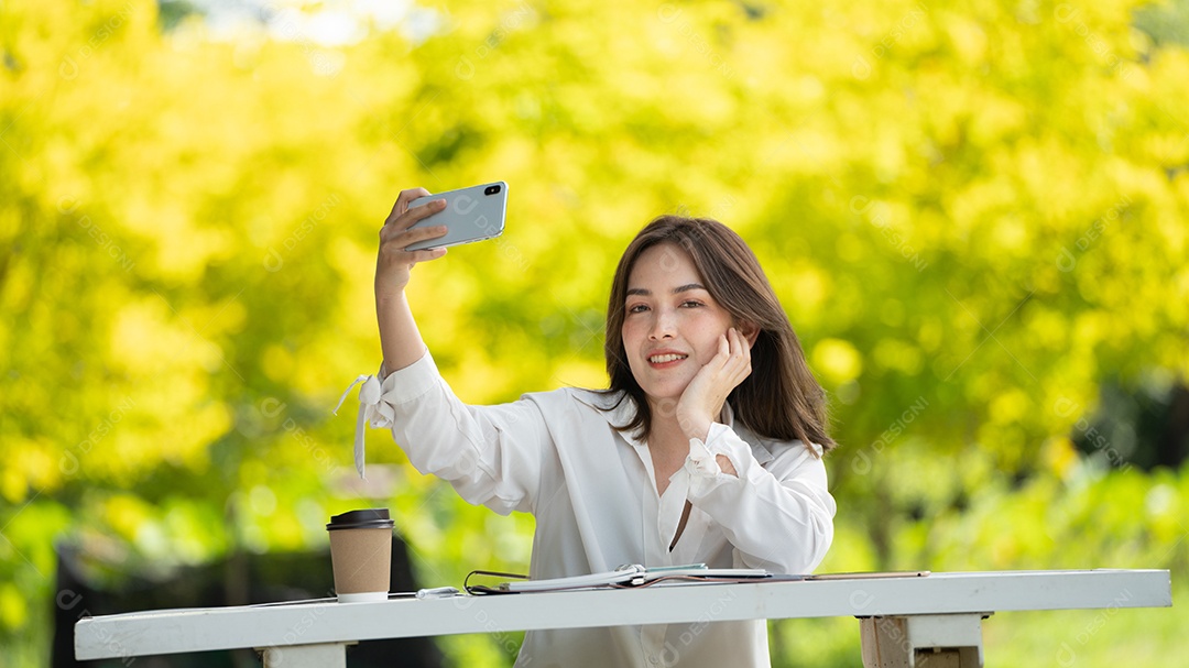 Mulher de sorriso pensativo no parque usando telefone inteligente.