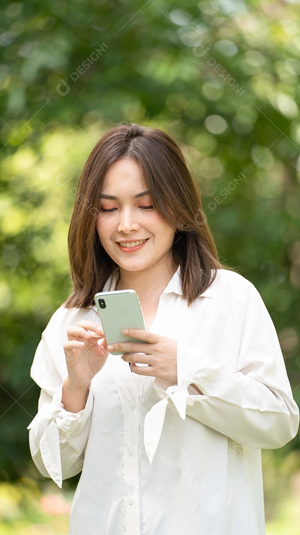 Mulher de sorriso pensativo no parque usando telefone inteligente.