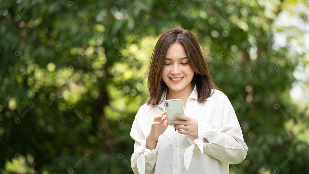 Mulher de sorriso pensativo no parque usando telefone inteligente.
