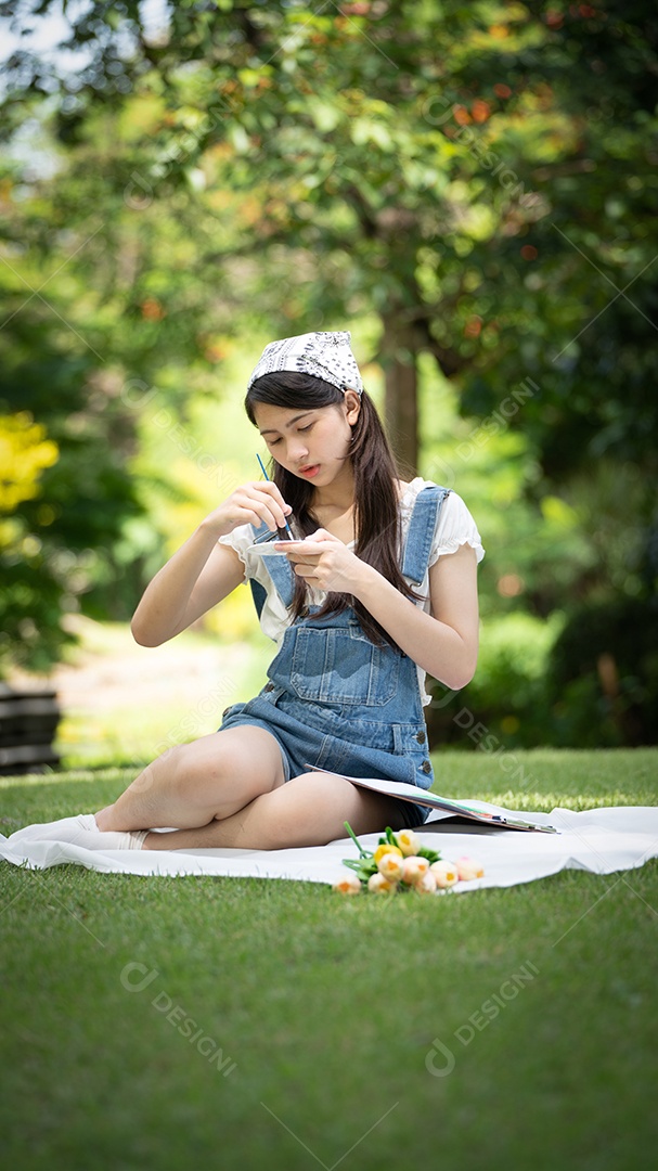 Encantadora mulher sentada na manta no parque no verão ensolarado.