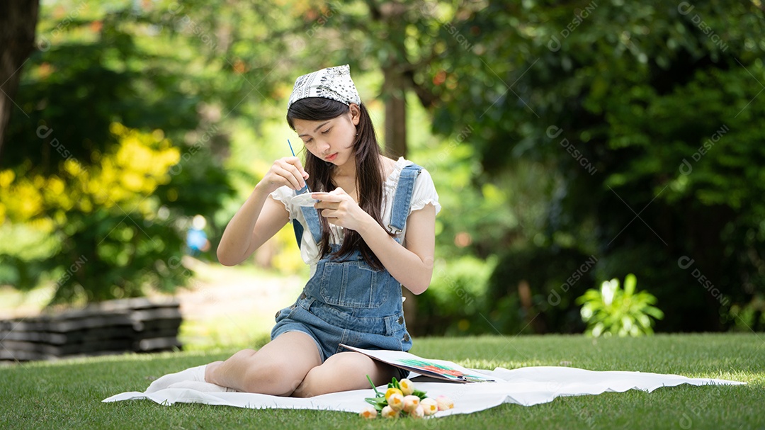 Encantadora mulher sentada na manta no parque no verão ensolarado.