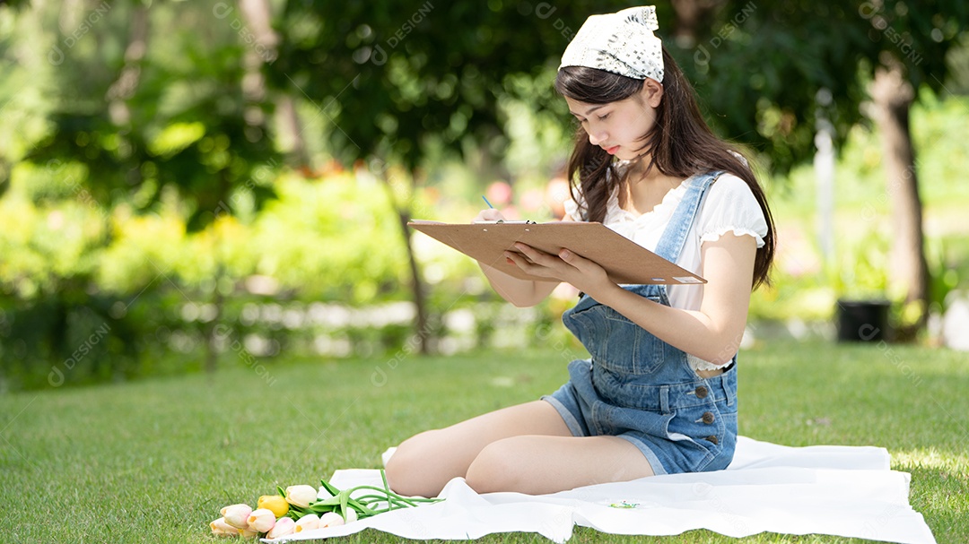 Encantadora mulher sentada na manta no parque no verão ensolarado.