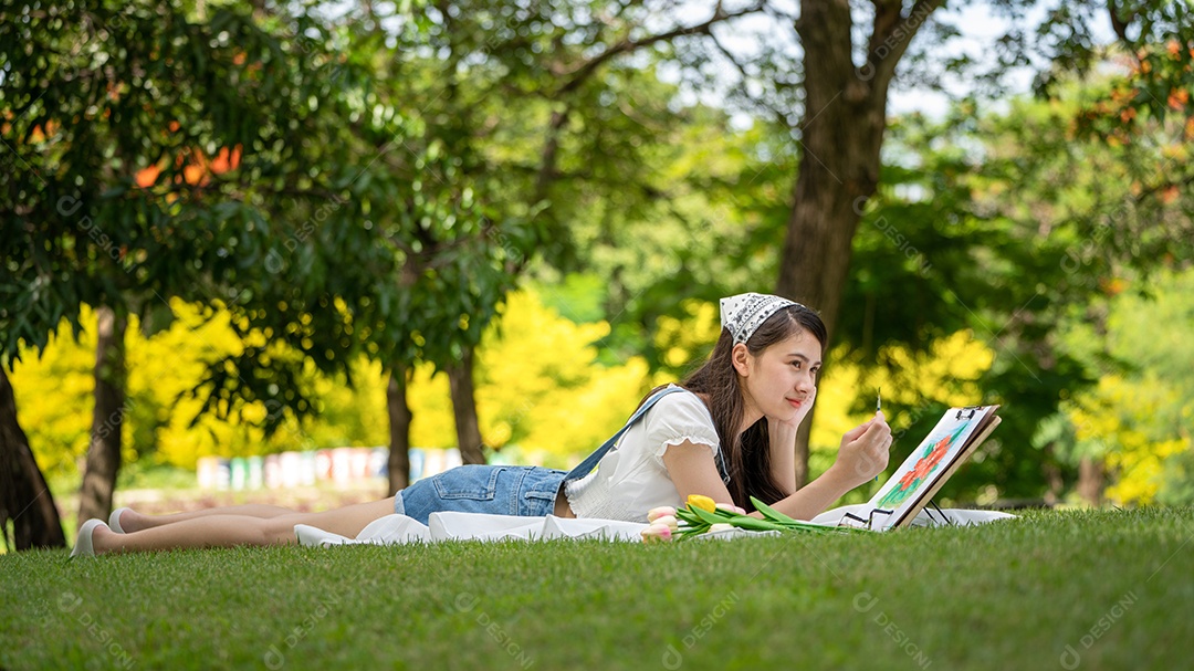 Encantadora mulher sentada na manta no parque no verão ensolarado.