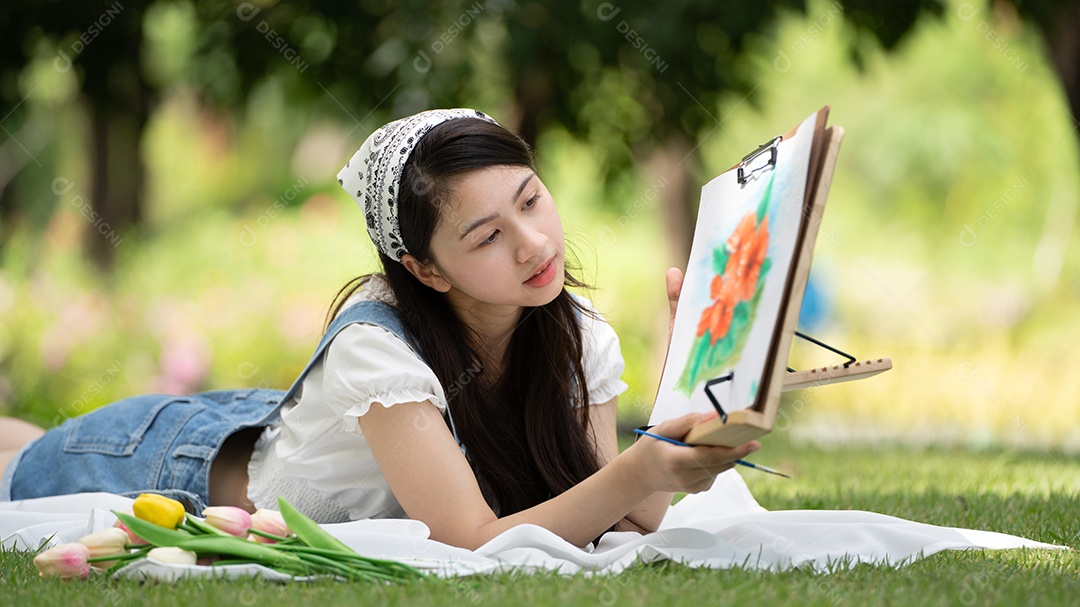 Encantadora mulher sentada na manta no parque no verão ensolarado.