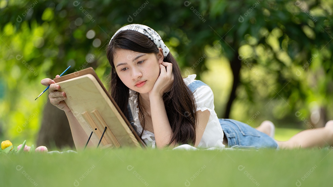 Encantadora mulher sentada na manta no parque no verão ensolarado.