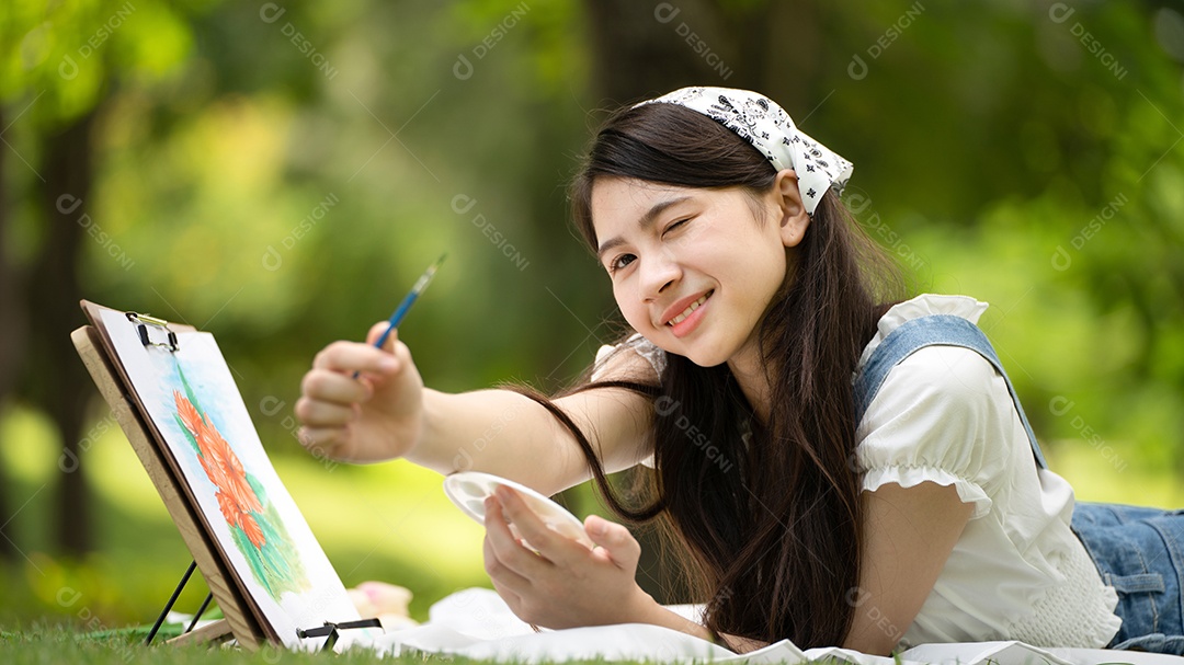 Encantadora mulher sentada na manta no parque no verão ensolarado.