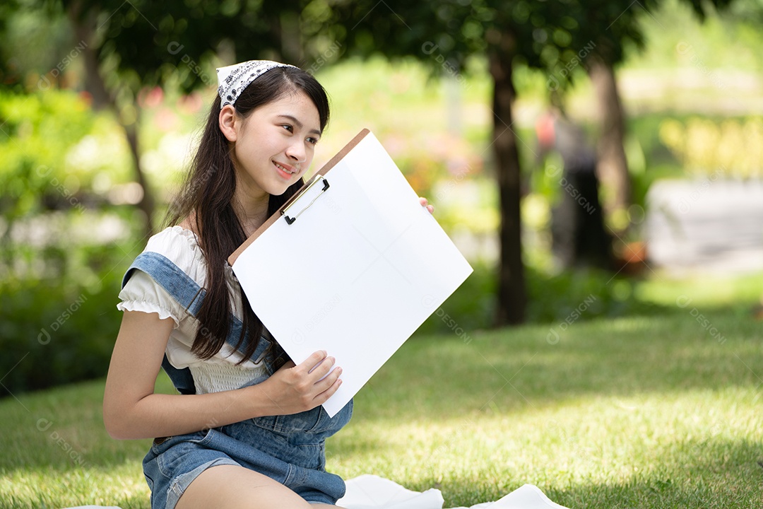 Encantadora mulher sentada na manta no parque no verão ensolarado.