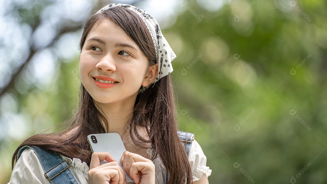 Retrato de menina mexendo no celular e fazendo gestos no parque verde da cidade verde em spri