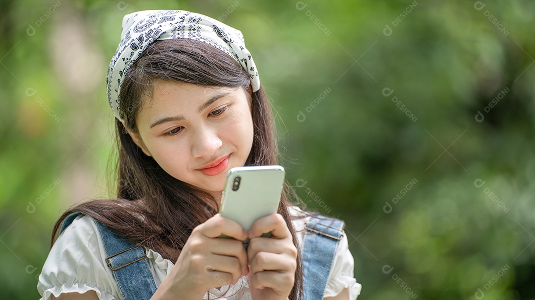 Retrato de menina mexendo no celular e fazendo gestos no parque verde da cidade verde em spri