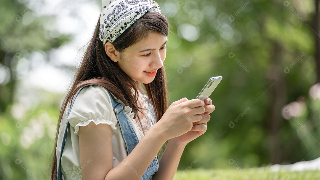 Retrato de menina tirando foto com celular e fazendo gestos no parque verde da cidade verde em spri