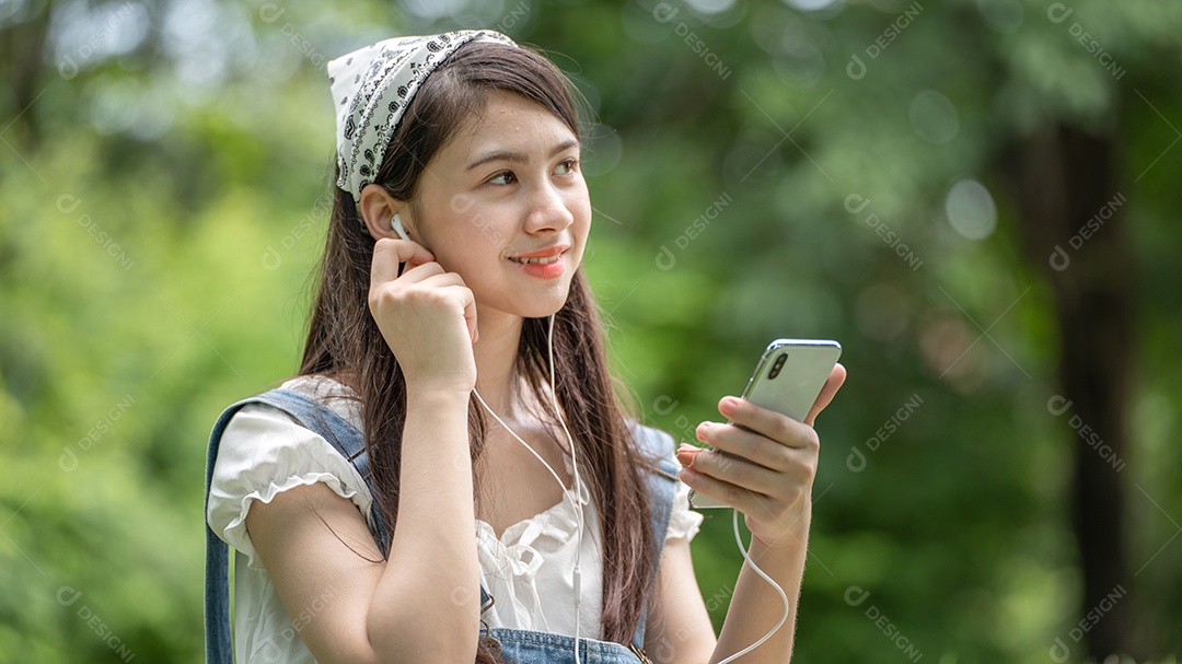 Retrato de menina com fones de ouvido escutando musicas fazendo gestos no parque verde da cidade verde em spri
